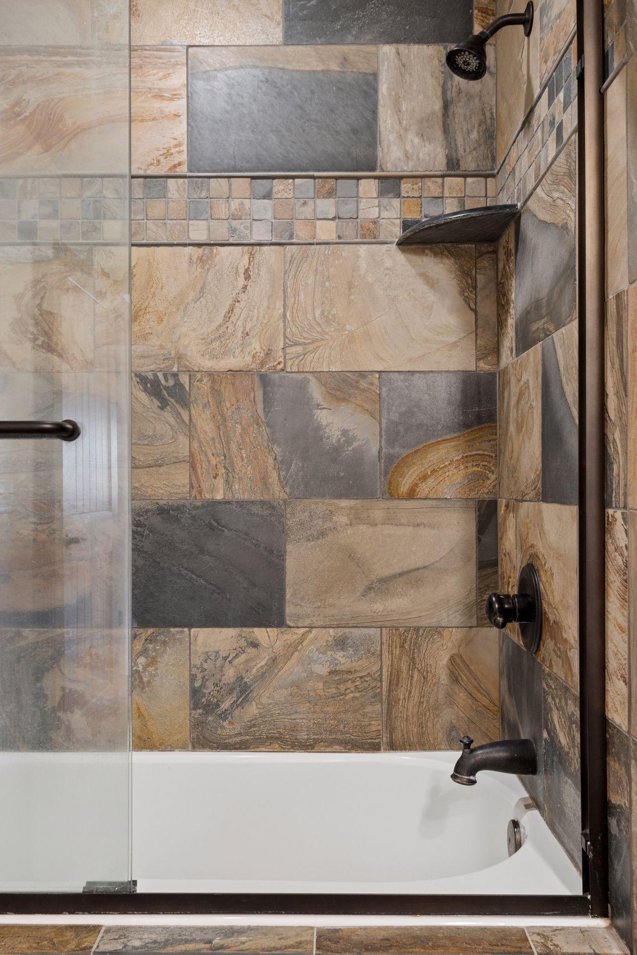 Custom tile tub/shower with glass enclosure and rich natural stone finishes