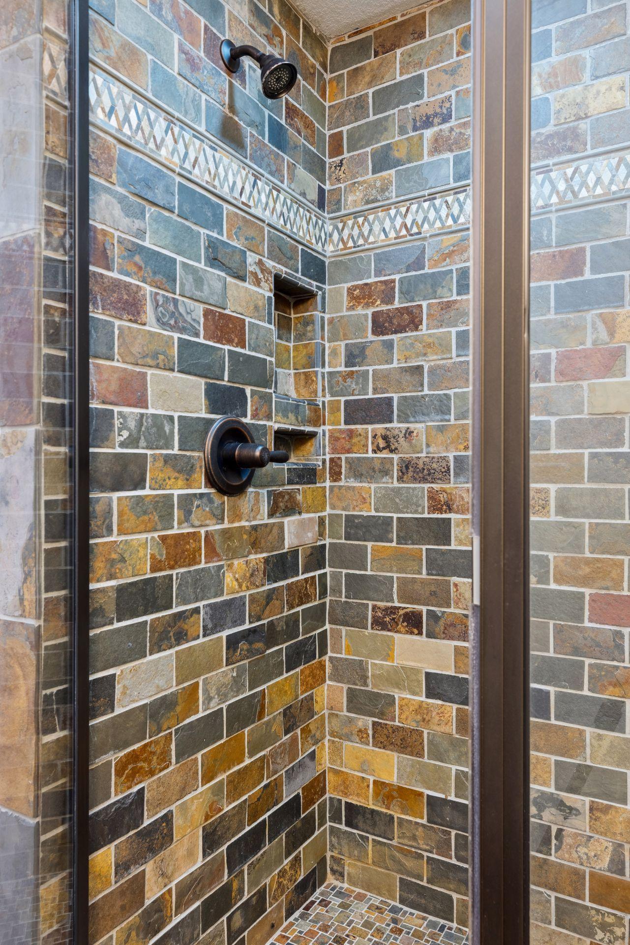 Walk-in tiled shower with glass enclosure and detailed stonework accents