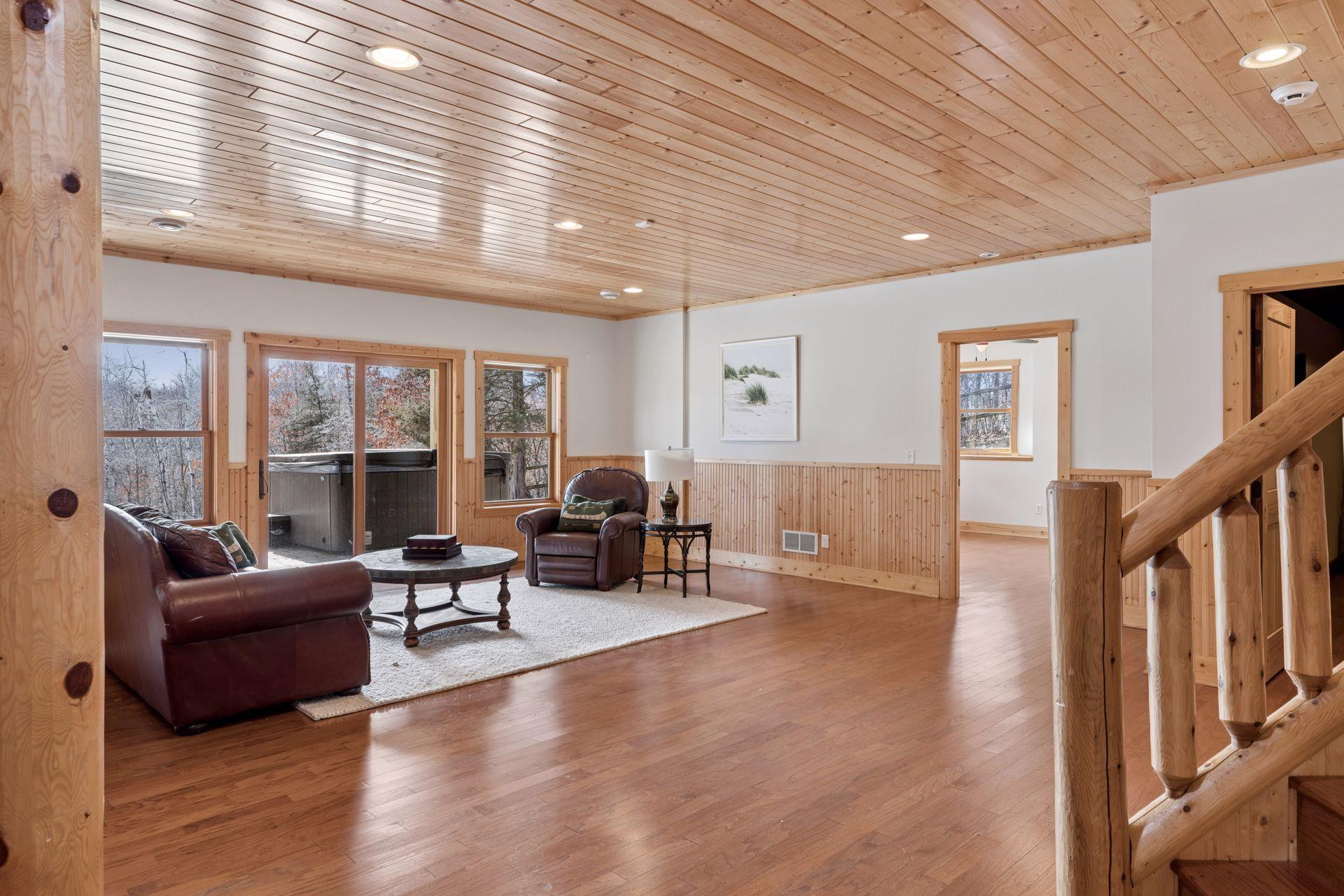 Spacious lower-level family room with wood ceilings, warm finishes, and walkout access to the patio