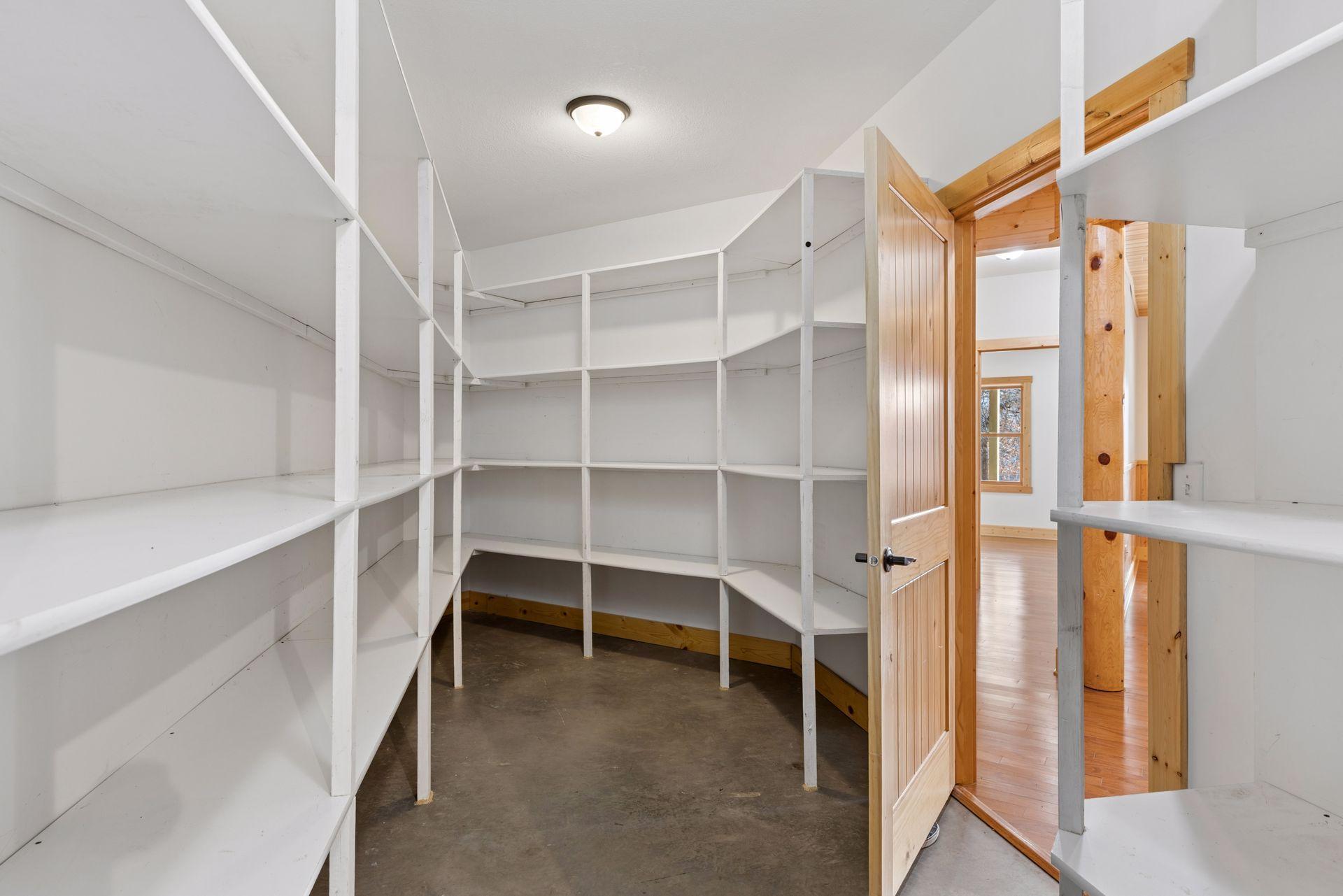 Generous storage room with built-in shelving for organization and utility is attached to the mechanical room for added convenience