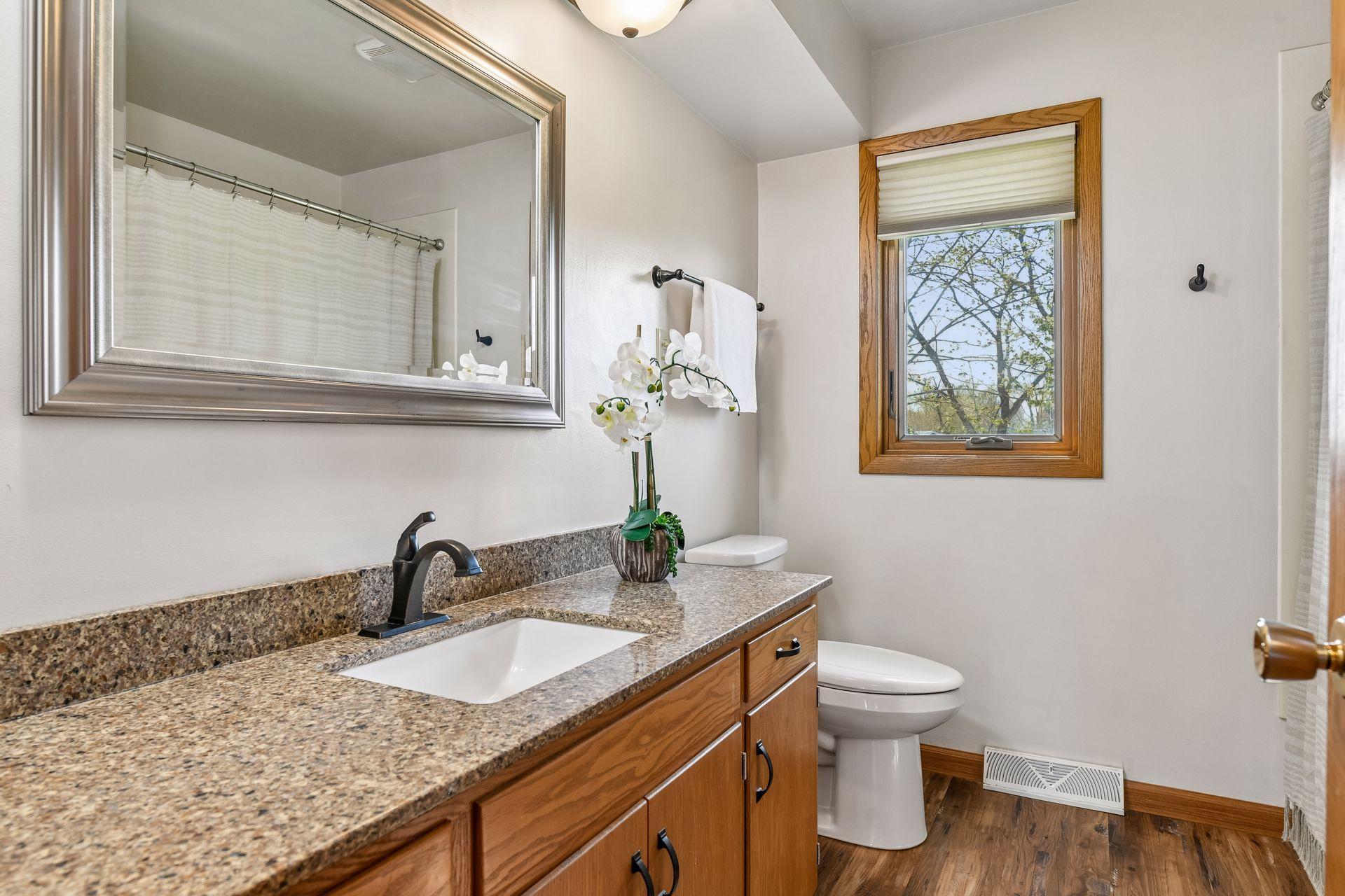 Primary bathroom features granite counters and shower/tub combo