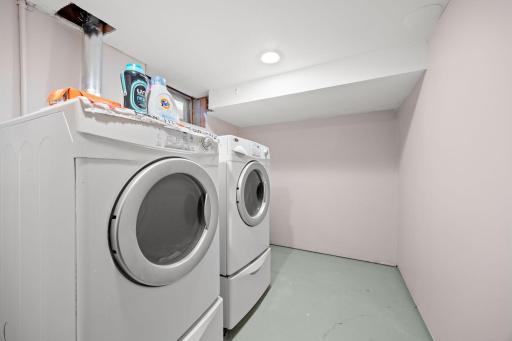 Nice-sized lower level laundry room with front loading washer & dryer on upgraded pedestal drawers.