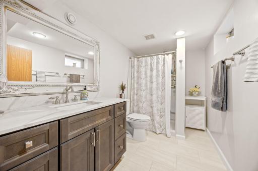 Spacious lower level 3/4 quarter bathroom with a modern vanity and countertop, plus newer flooring, faucet, & more.