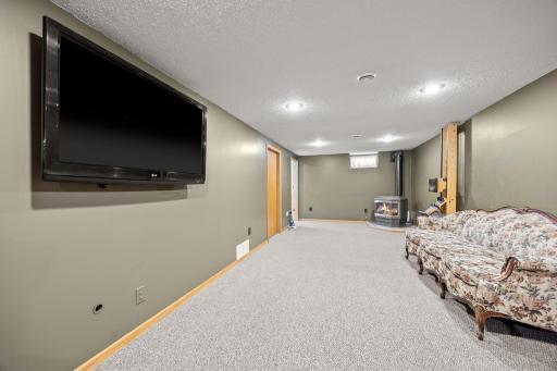 Giant family room in the lower level with a gas fireplace, mounted tv (included), bathroom, & laundry room. Recessed lighting modernizes the space.
