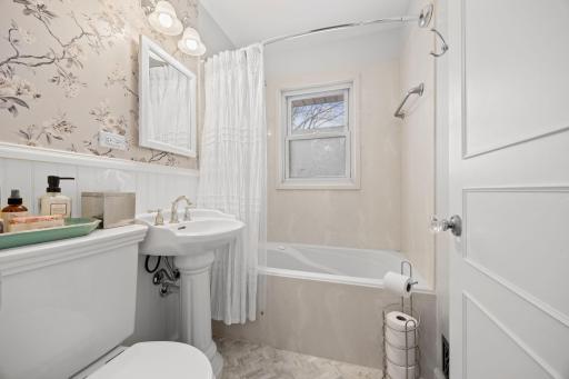 Renovated full main level bathroom with pedestal sink, newer toilet, gorgeous tile flooring, wainscoting, new fan w/proper ventilation, & more.