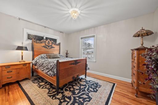 Spacious primary bedroom with the same refinished hardwood oak flooring, white trim, sanded ceilings/walls, new light fixture, & top down blind.