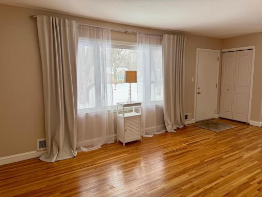 Huge living room shown vacant. Gleaming floors, lots of natural light, and beautiful curtains are included.