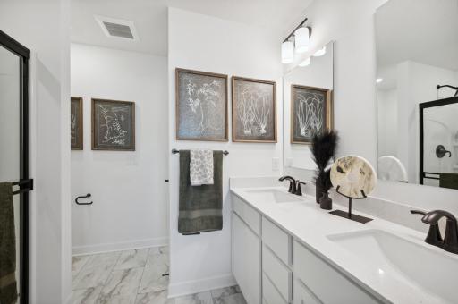 The owner's bathroom offers a double-vanity with quartz countertops, a linen closet, and shower. (Photo of Actual Home)