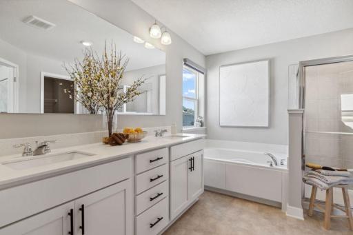 The primary suite bathroom, featuring dual sinks, both an extra deep soaking tub and oversized walk-in shower! Model home, color and finish will vary.