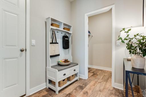 The large mudroom includes a walk in closet and space for a table, bench or lockers! The main floor bedroom and 3/4 bath are directly ahead. Photo of model home, colors and finishes are similar.