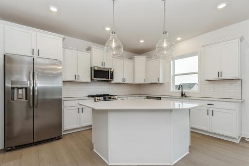 (Photo of a decorated model, actual homes finishes and colors will vary) The Sinclair features a stunning gourmet kitchen with a large center island, quartz countertops, LVP floors, stainless steel appliances, and more.