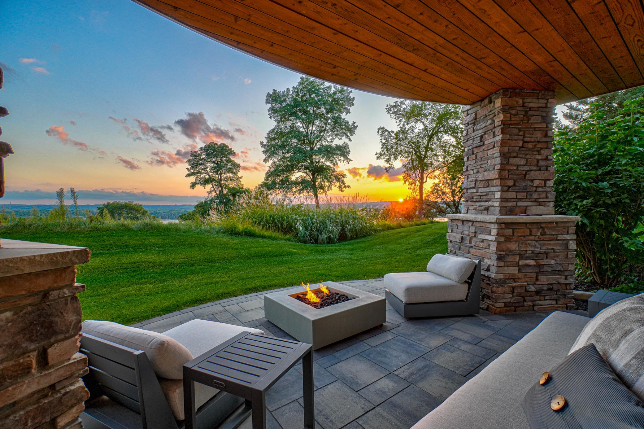 The covered patio embraces outdoor living with panoramic river and sunset views.
