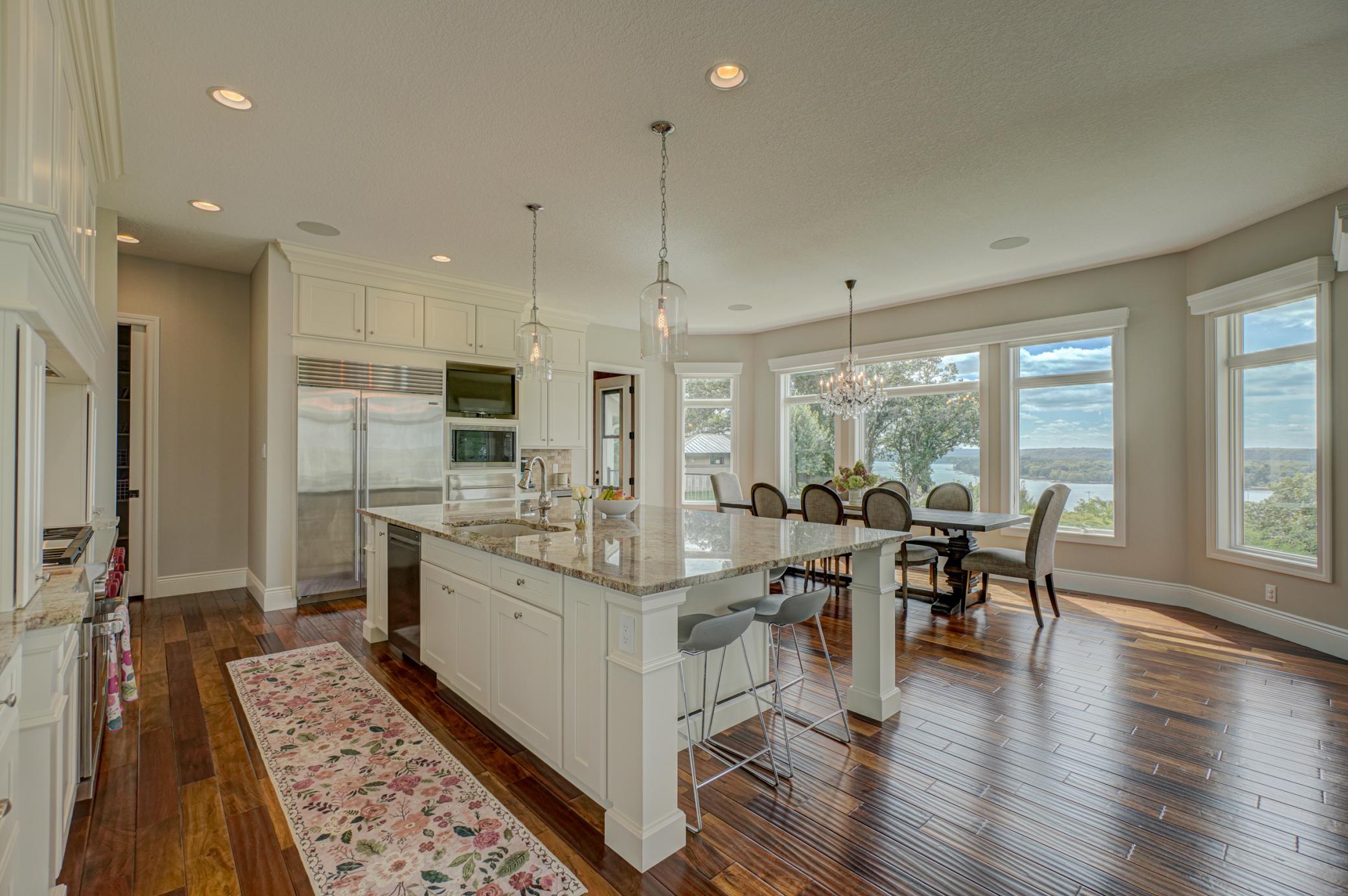 The gourmet kitchen is both expansive and elegant, anchored by a grand center island featuring granite countertops. Professional-grade appliances, including a Sub-Zero fridge & Wolf range, elevate the space.