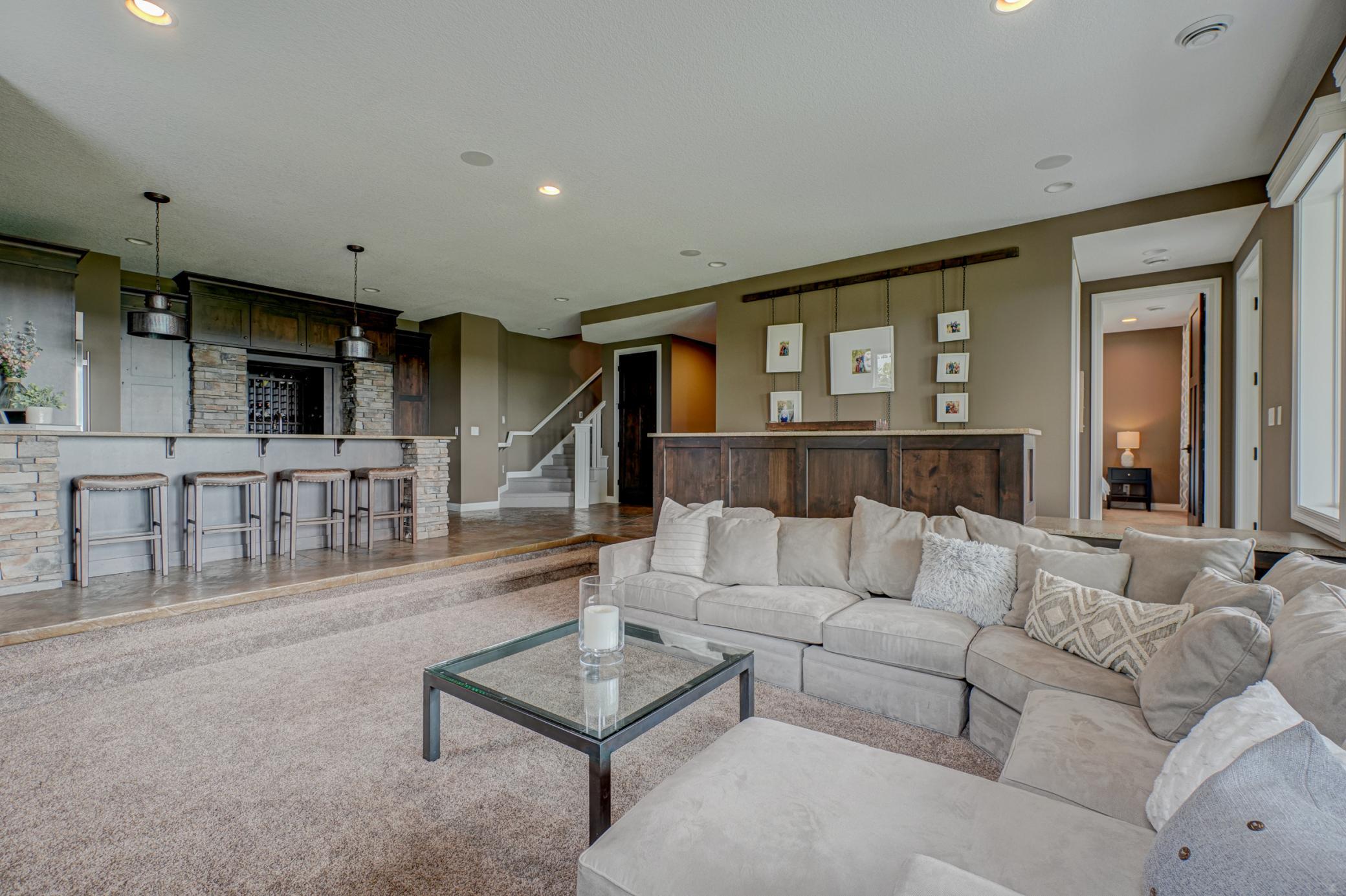 The finished walkout lower level is designed for entertaining, complete with a beautiful kitchen and bar, a luxe wine cellar, sleek stone fireplace, and expansive windows.