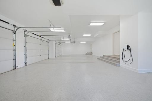 The oversized four-car garage features a Spancrete design with heated epoxy floors, and a mirrored tuck-under storage below, offering exceptional space for vehicles, recreational equipment, and more.