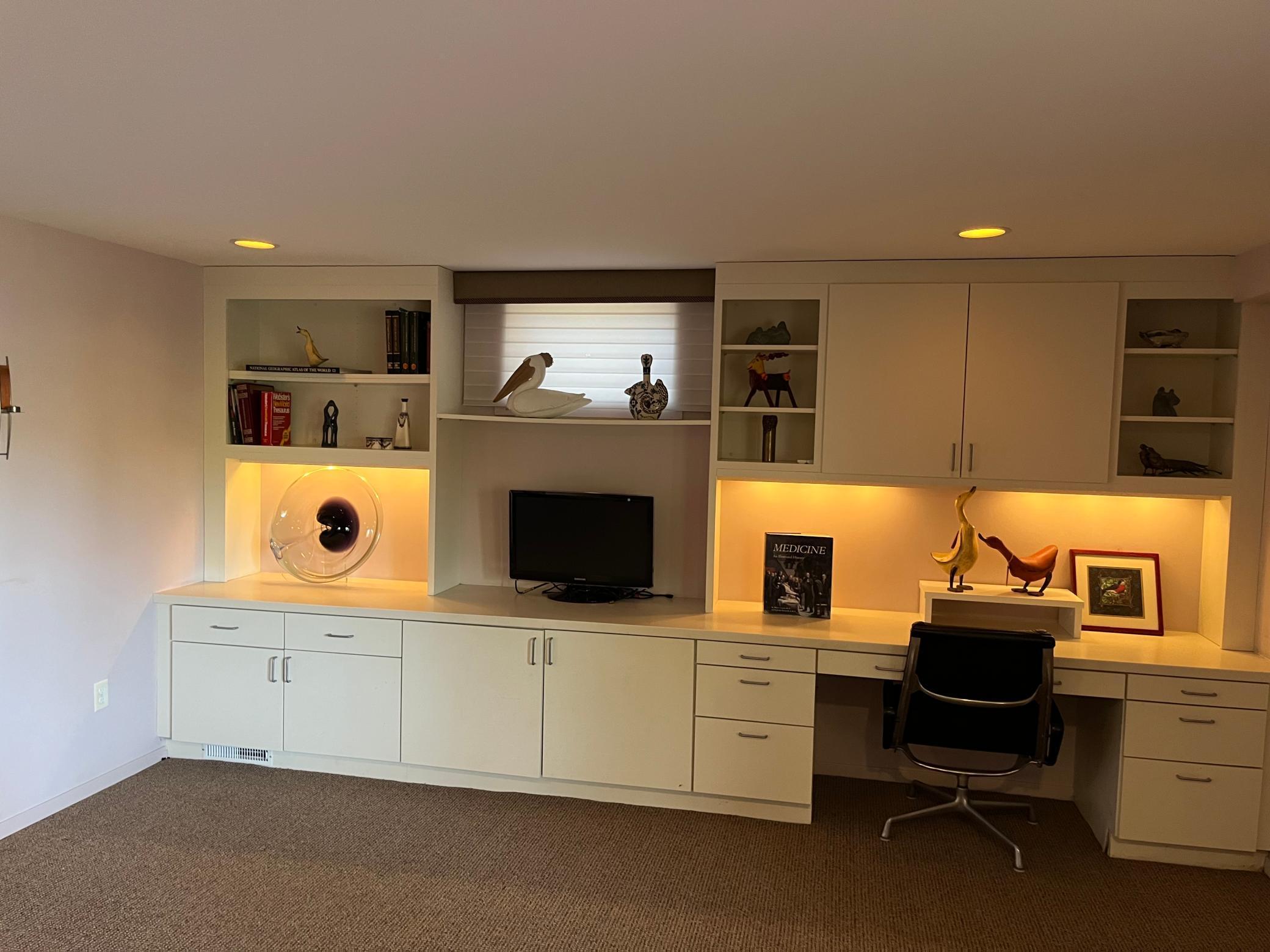 An entire wall of office desks and bookshelves at end of lower living room.