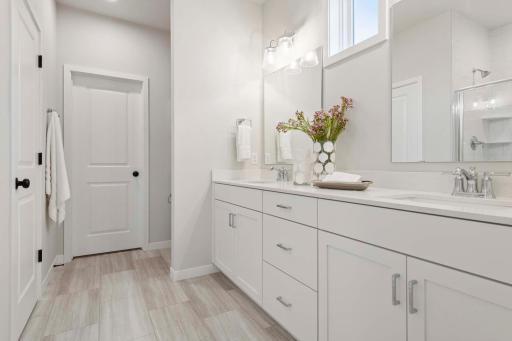 The primary en-suite is a luxurious and functional space designed for daily comfort and relaxation. Featuring dual sinks. and modern fixtures. Photos are of previously built home; options & features will vary.