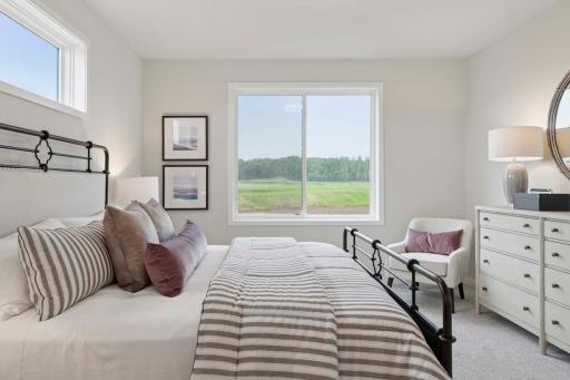 The main level primary bedroom is a serene retreat designed for comfort and relaxation. Spacious and bright, it features large windows that invite natural light. Photos are of previously built home; options & features will vary.