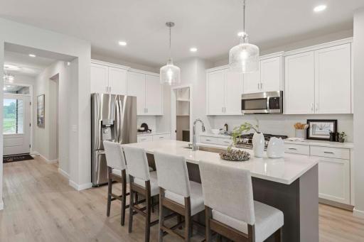 Designer island pendants hang elegantly above the kitchen island, adding a touch of sophistication and style. Photos are of previously built home; options & features will vary.