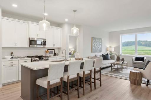 The efficient kitchen is thoughtfully designed to maximize space, function, and style. At its heart is a large central island topped with sleek quartz countertops, Photos are of previously built home; options & features will vary.