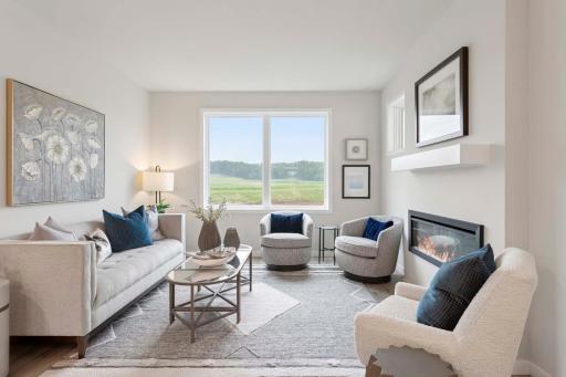 The gathering room on the main level is a warm welcoming space designed for connection and comfort. Large windows invite natural light throughout the day Photos are of previously built home; options and features will vary.