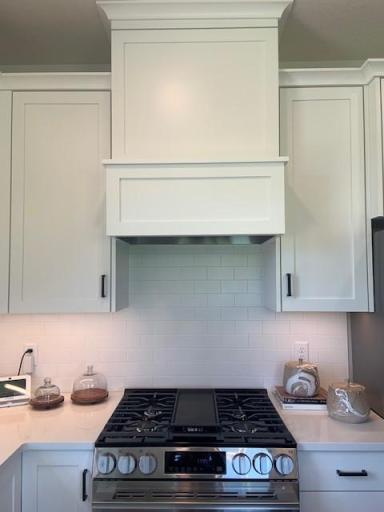 LG Gas range and wood hood with ceramic tiled kitchen backsplash.