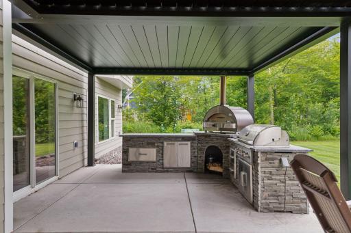 Step outside to a well-appointed backyard retreat featuring a back patio with electronic metal pergola, a full outdoor kitchen, and a wood-fired pizza ovenâideal for alfresco entertaining.