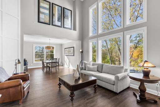 Open living room with soaring ceilings, expansive floor to ceiling windows flows seamlessly into the dining space and beyond.