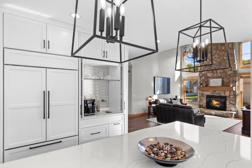 Coffee bar is tucked into custom cabinetry, complete with open shelving, facet and sink.