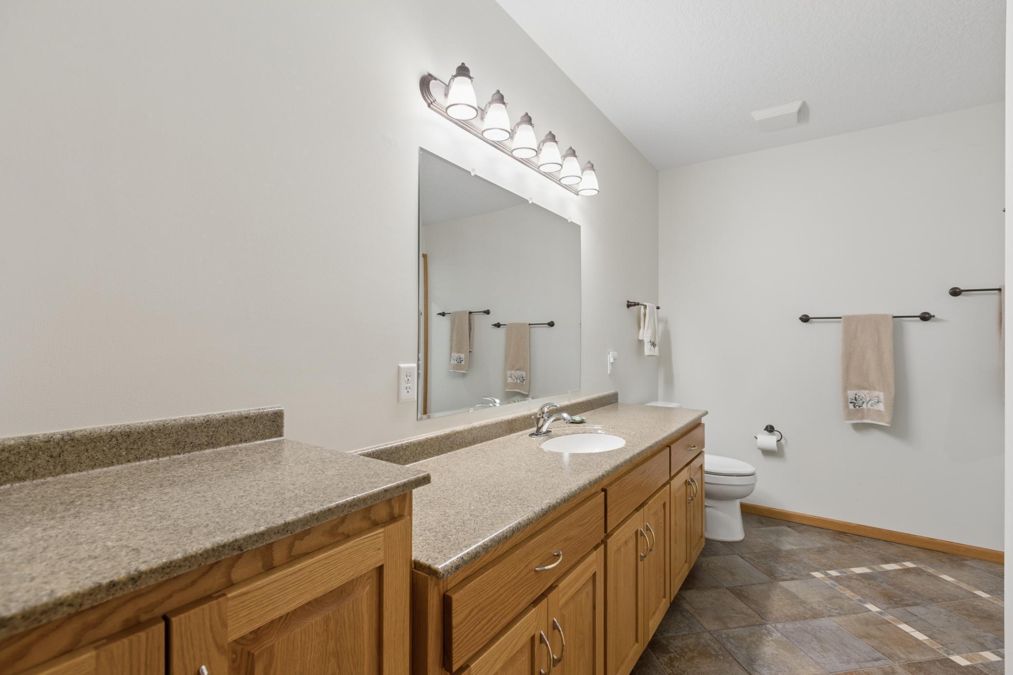 The full bathroom in the lower level offers plenty of vanity space and storage. Featuring heated tile floors and a steam shower.