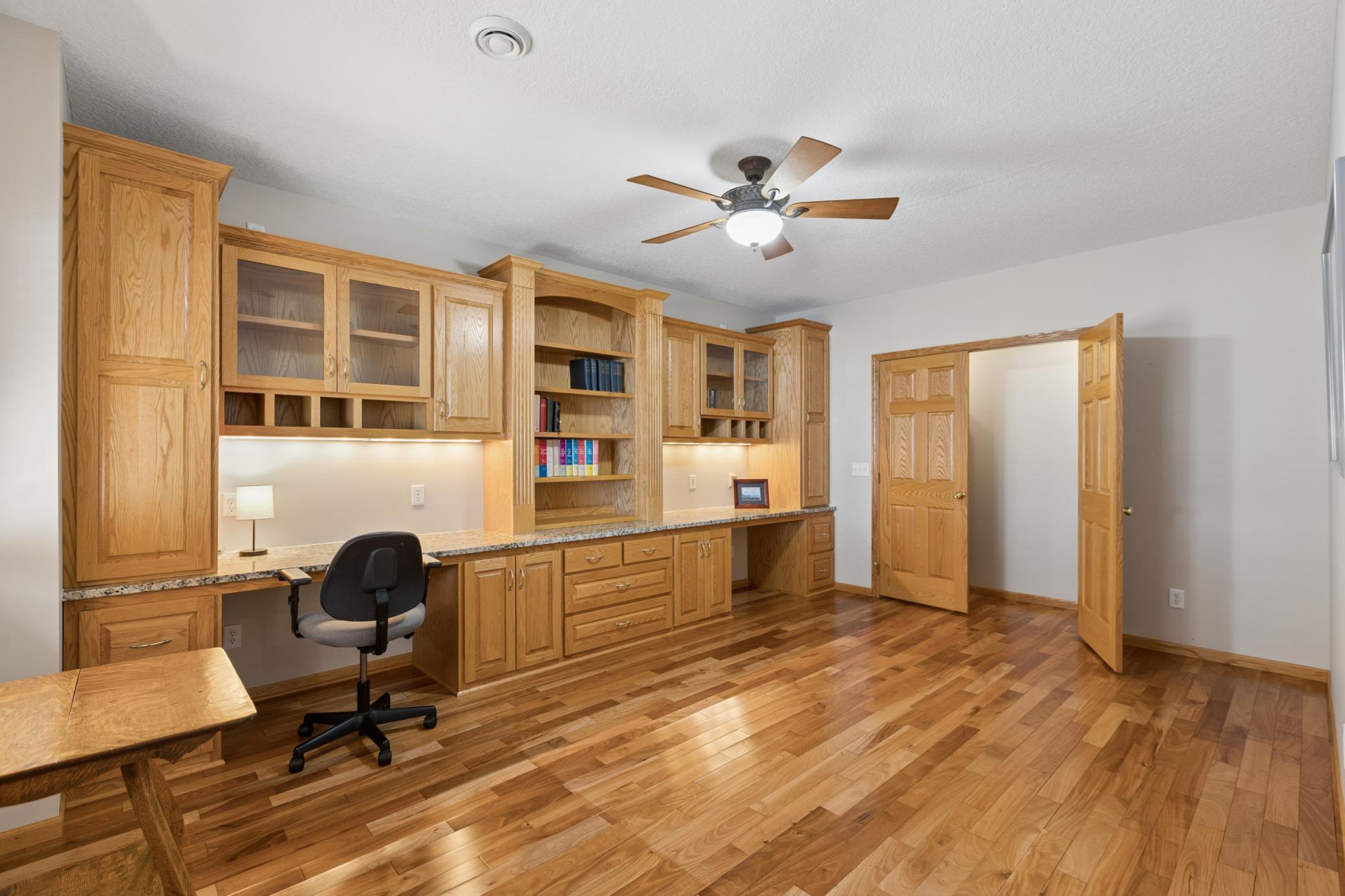 View of the fourth bedroom with build in desks with bookcases and a French door closet.