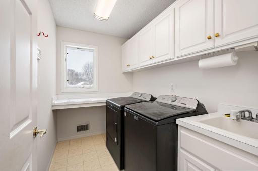 Main Floor Laundry with utility sink and extra storage cabinets