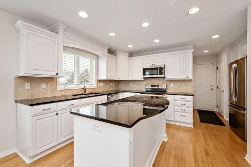 Updated kitchen with granite countertops, tile backsplash, center island, hardwood floors, wine refrigerator and breakfast bar!