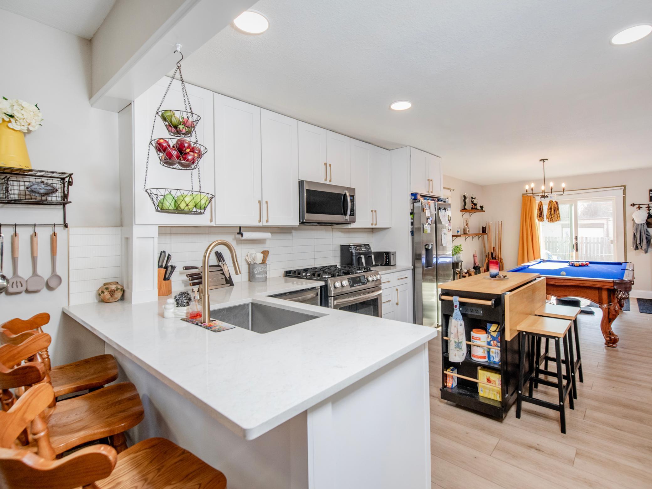 Open, eat-in kitchen with stainless steel appliances and tile backsplash.