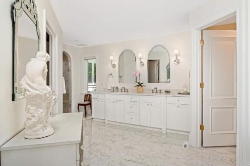 The owner's suite consists of dual sinks and private water closet (door on the right), walk-in closet (to the left) and arched marble shower. Beautiful custom cabinetry at vanity, and also in water cl