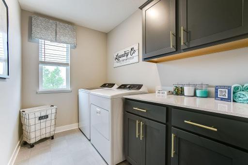 Upper-level laundry with washer and dryer connections included. Leveled up with built-in cabinetry and quartz countertops. Love the window! Photo of model home, colors and finishes will vary.