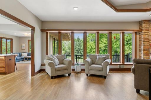 Wrapped in floor-to-ceiling windows, the living room offers panoramic views of the wooded backyard, pulling nature into every moment.