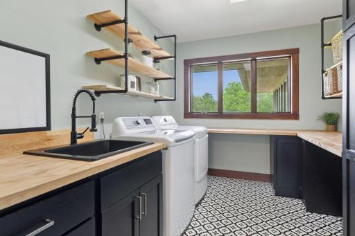 Spacious and thoughtfully designed, this laundry room makes tackling chores a little easier. Butcher block counters provide generous space for folding and sorting, while industrial pipe shelving keeps essentials organized and within reach.