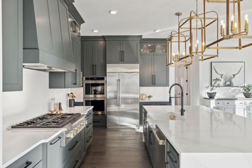 The gourmet kitchen is a showstopper complete with high-end appliances, an oversized island, quartz countertops, and elegant brass lighting fixtures.