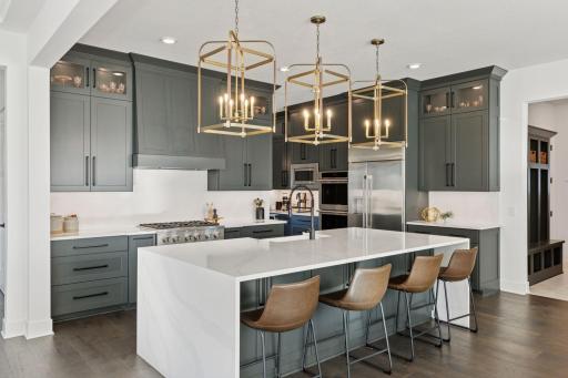 The gourmet kitchen is a showstopper complete with high-end appliances, an oversized island, quartz countertops, and elegant brass lighting fixtures.