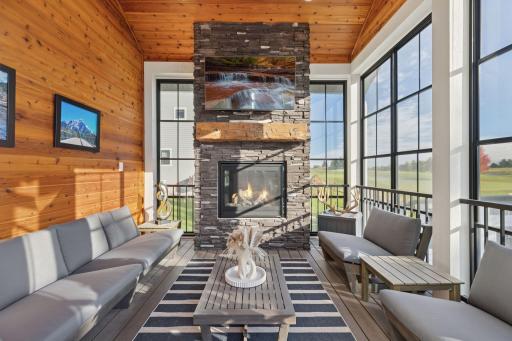 With access to both the expansive outdoor deck and kitchen, the screened porch with fireplace, Eze-Breeze windows, and wood-paneled ceiling overlooks lush fairways, greens, and sunset views.