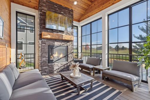 With access to both the expansive outdoor deck and kitchen, the screened porch with fireplace, Eze-Breeze windows, and wood-paneled ceiling overlooks lush fairways, greens, and sunset views.