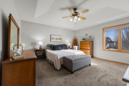 Spacious primary bedroom features tray ceiling, neutral decor and great natural light.