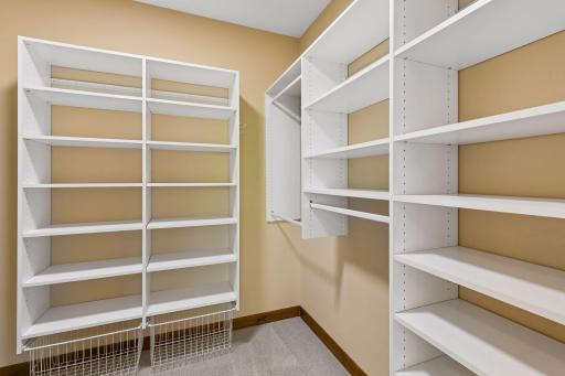 Spacious primary walk-in closet with custom built in organizers.