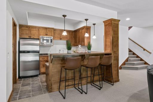 An entertainer's delight! The lower-level wet bar includes custom cabinetry, bar seating, and ample space for hosting gatherings.
