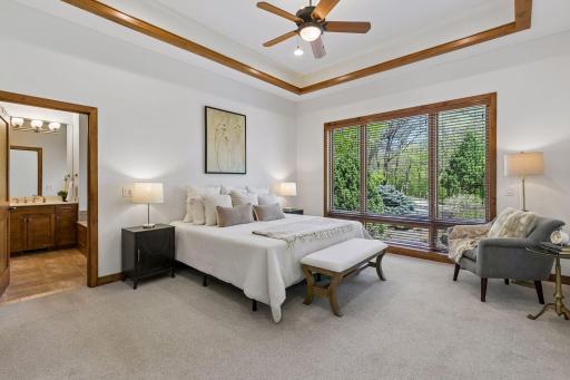 Retreat to the spacious primary suite featuring French door entry, tray ceiling w/rich wood accent and ambient lighting, walk-in closet and private full bath. A peaceful, light-filled space designed for comfort & relaxation.
