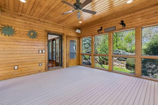 Another view of the screened porch featuring a warm wood ceiling, composite flooring, ceiling fan and peaceful views. An ideal space to relax or entertain!