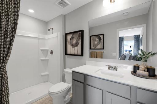 Private en suite bathroom off primary with double vanity and walk-in shower. (Model photo, colors may vary)