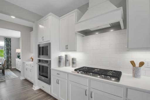 Gourmet kitchen with cooktop, wood hood, wall microwave and oven. Imagine cooking here! Model photo. Options and colors will vary.