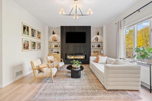 Main floor family room designed for gatherings with the electric fireplace, open shelves, and large windows to the private back yard that sits on the Crow River.